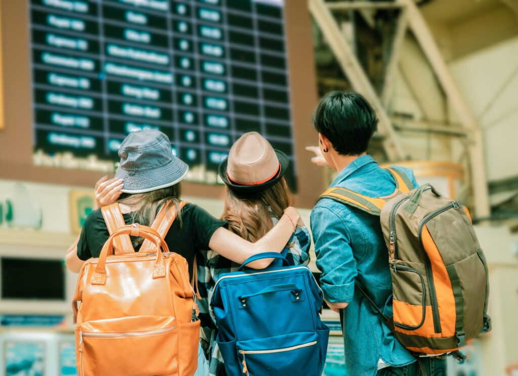 Gruppo di amici viaggiatori con il bancone dei biglietti e lo sfondo degli orari.