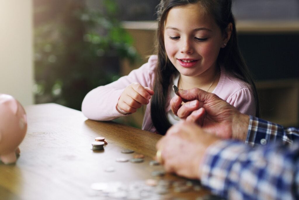 Soldi, salvadanaio e monete con bambino e nonno per risparmi, investimenti e apprendimento